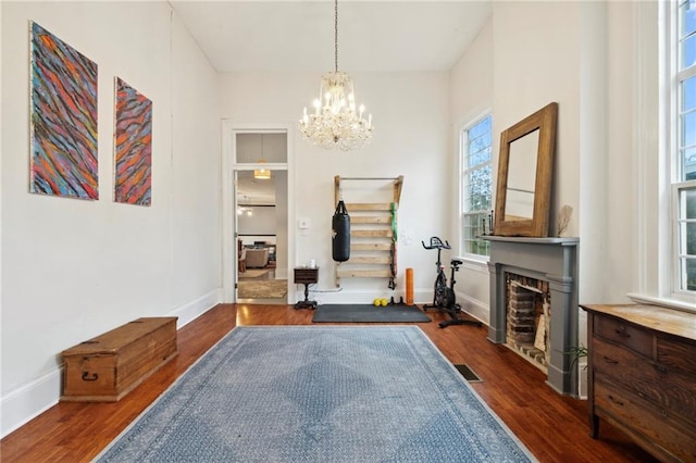 living area featuring a chandelier, dark wood-type flooring, and a healthy amount of sunlight