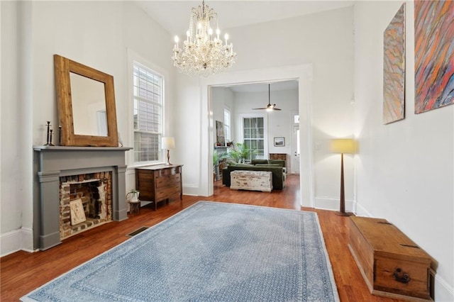 living area with wood-type flooring, ceiling fan with notable chandelier, and a fireplace