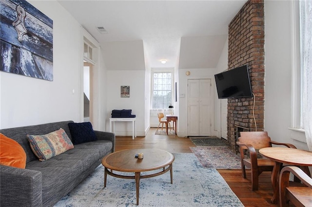 living room featuring lofted ceiling, hardwood / wood-style flooring, and a fireplace