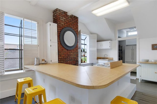 kitchen with a wealth of natural light, kitchen peninsula, dark hardwood / wood-style floors, and a breakfast bar area