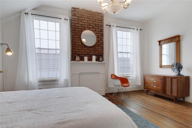 bedroom featuring hardwood / wood-style flooring, lofted ceiling, a chandelier, and multiple windows