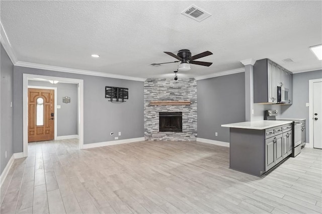 kitchen featuring gray cabinetry, a textured ceiling, stainless steel appliances, a fireplace, and light hardwood / wood-style floors