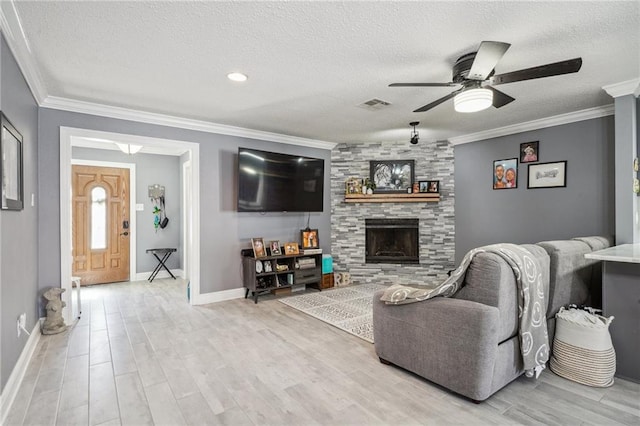 living room with ceiling fan, a stone fireplace, a textured ceiling, and light hardwood / wood-style floors