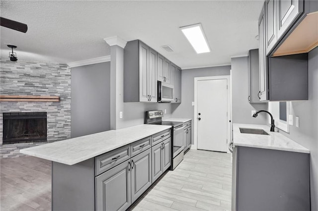 kitchen with gray cabinets, stainless steel appliances, kitchen peninsula, and sink