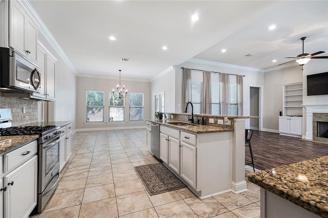 kitchen with a kitchen bar, appliances with stainless steel finishes, decorative backsplash, a high end fireplace, and sink