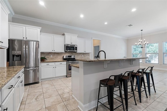 kitchen with a kitchen bar, a kitchen island with sink, stainless steel appliances, and an inviting chandelier