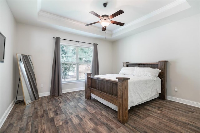 bedroom with ceiling fan, crown molding, dark wood-type flooring, and a tray ceiling