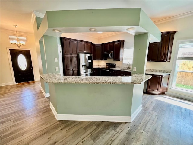 kitchen with a notable chandelier, stainless steel appliances, hanging light fixtures, and light hardwood / wood-style flooring