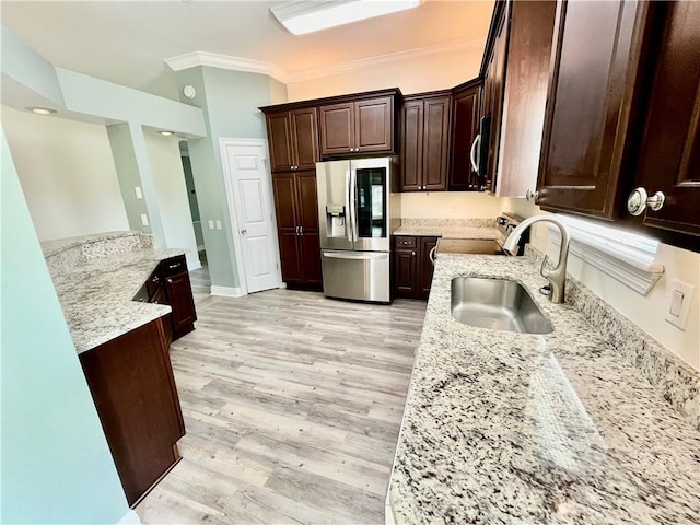 kitchen with light stone counters, dark brown cabinetry, ornamental molding, light hardwood / wood-style flooring, and stainless steel appliances