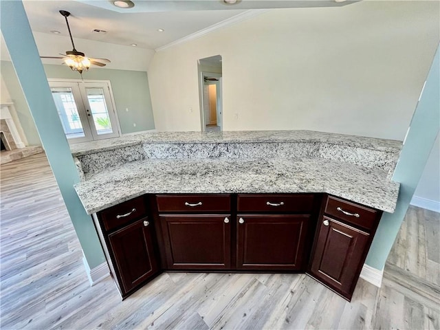 kitchen featuring light wood-type flooring, kitchen peninsula, ornamental molding, ceiling fan, and light stone countertops