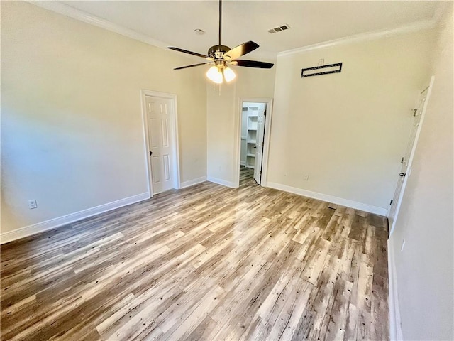 empty room featuring light wood-type flooring, ceiling fan, and crown molding