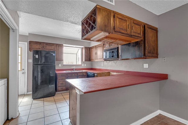 kitchen featuring a textured ceiling, light tile patterned flooring, kitchen peninsula, and black appliances