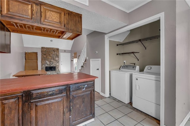 laundry room featuring a stone fireplace, light tile patterned floors, a textured ceiling, and washer and dryer