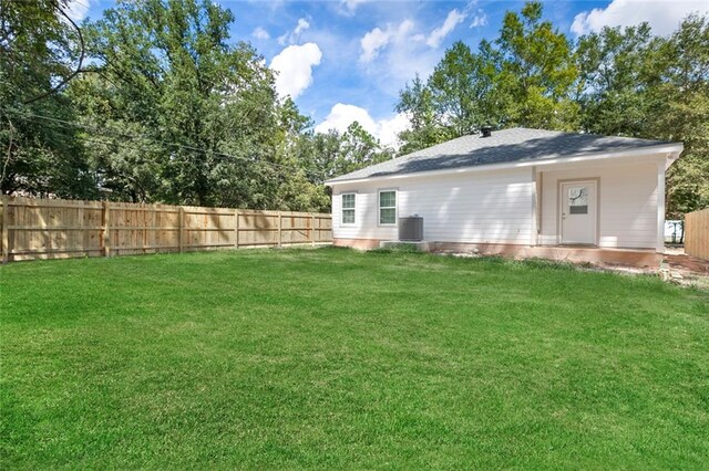 rear view of house with a lawn and cooling unit