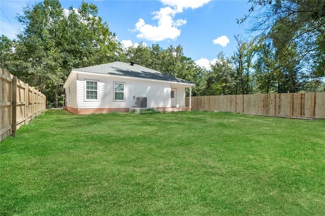 back of property featuring central air condition unit and a yard