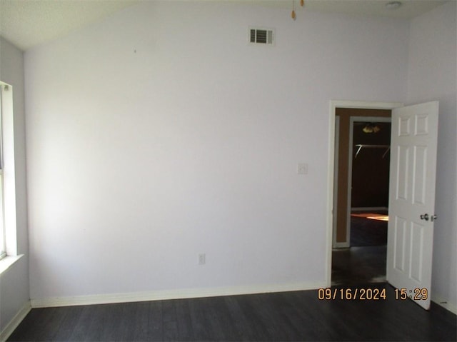 spare room featuring vaulted ceiling and dark hardwood / wood-style flooring