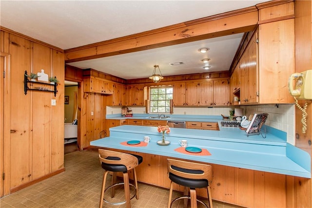 kitchen with backsplash, kitchen peninsula, a kitchen bar, stainless steel dishwasher, and sink