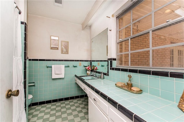 bathroom with tile walls, vanity, and toilet