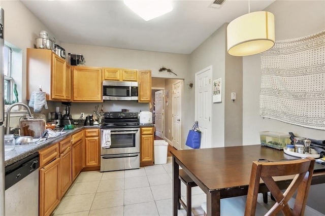 kitchen featuring sink, stainless steel appliances, hanging light fixtures, and light tile patterned floors