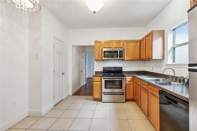 kitchen with an inviting chandelier, light tile patterned flooring, sink, and stainless steel appliances