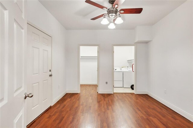 unfurnished bedroom featuring a spacious closet, wood-type flooring, ceiling fan, and independent washer and dryer