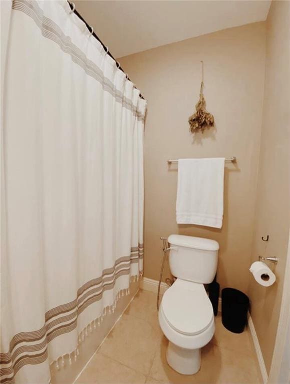 bathroom featuring tile patterned flooring, toilet, and curtained shower