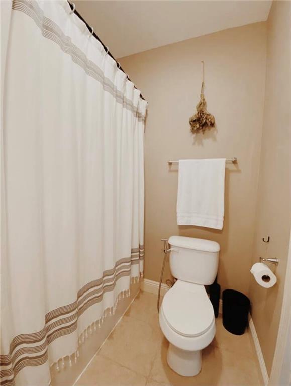 531-33 S Murat St, New Orleans, LA 70119 - bathroom featuring baseboards, a shower with shower curtain, toilet, and tile patterned flooring