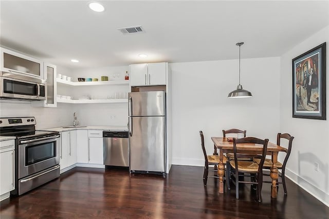 kitchen featuring dark hardwood / wood-style floors, pendant lighting, sink, white cabinetry, and appliances with stainless steel finishes