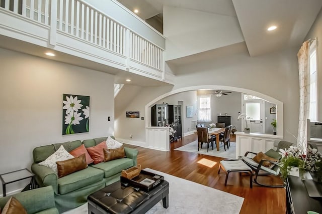 living room featuring ceiling fan, dark hardwood / wood-style floors, and a towering ceiling