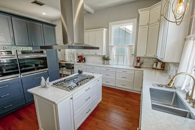 kitchen with white cabinetry, sink, exhaust hood, and decorative light fixtures