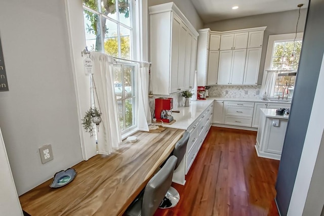 kitchen with decorative backsplash, white cabinets, wooden counters, and decorative light fixtures