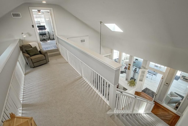 interior space featuring light colored carpet and vaulted ceiling with skylight