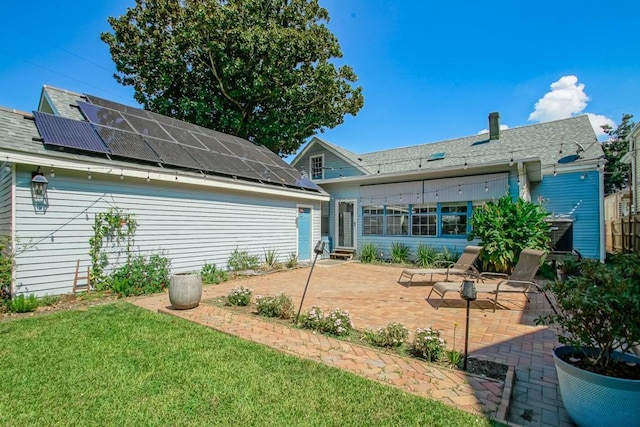 rear view of house featuring a yard, a patio, and solar panels