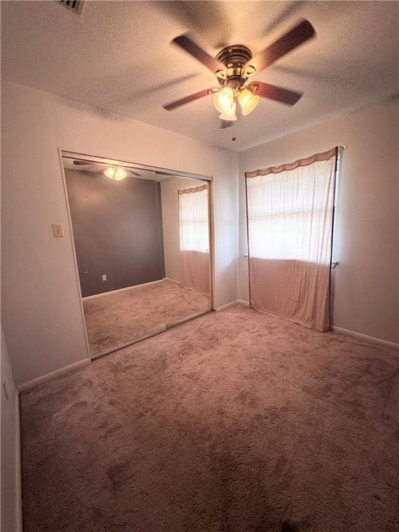 unfurnished bedroom with ceiling fan, carpet, a textured ceiling, and a closet