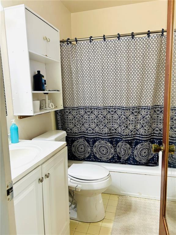 full bathroom with tile patterned flooring, vanity, shower / tub combo with curtain, and toilet