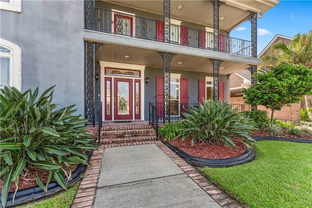 doorway to property with a balcony and a yard