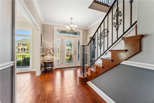 foyer entrance with wood-type flooring, ornamental molding, and a chandelier