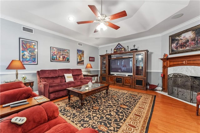 living room featuring a tray ceiling, ceiling fan, hardwood / wood-style flooring, and crown molding