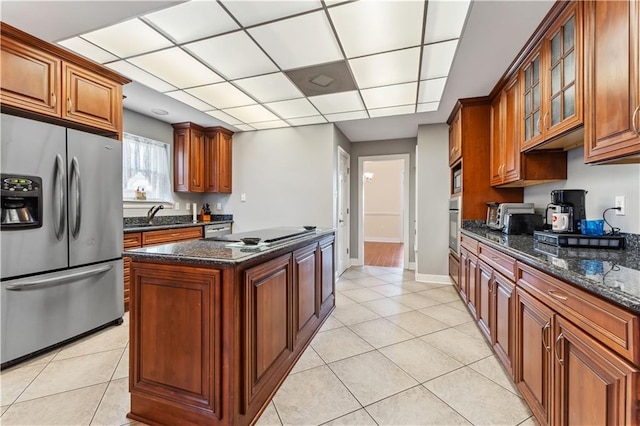 kitchen featuring appliances with stainless steel finishes, dark stone counters, a kitchen island, and light tile patterned floors