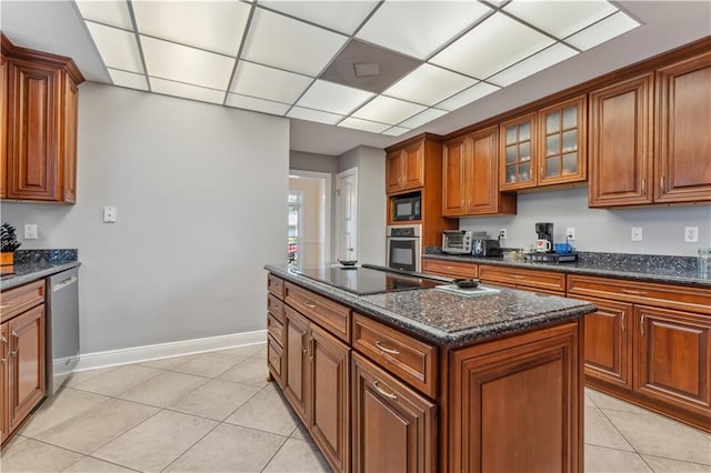 kitchen with dark stone countertops, a kitchen island, light tile patterned floors, and black appliances