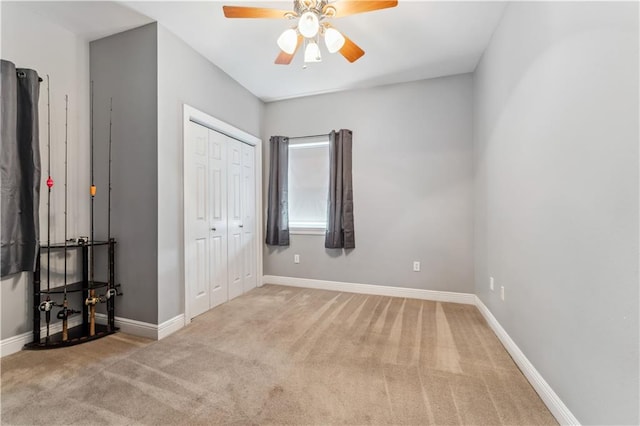 unfurnished bedroom featuring ceiling fan, light colored carpet, and a closet