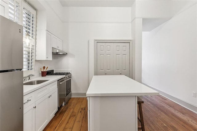 kitchen with appliances with stainless steel finishes, white cabinets, a breakfast bar area, light wood-type flooring, and sink