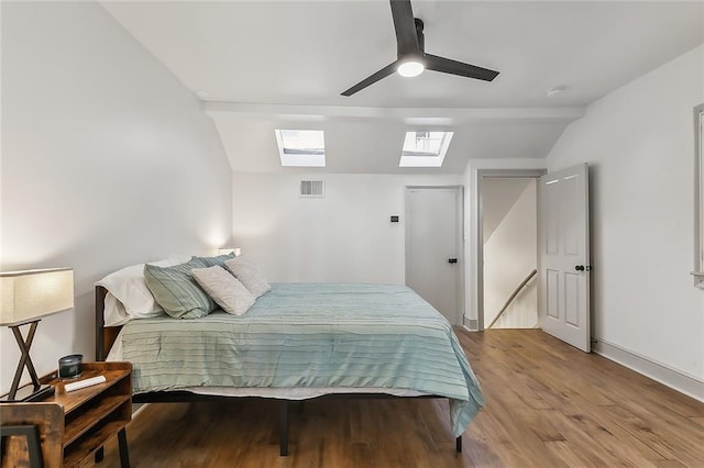 bedroom with light hardwood / wood-style flooring, vaulted ceiling with skylight, and ceiling fan