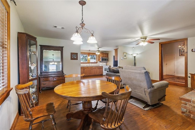 dining room with ceiling fan with notable chandelier, hardwood / wood-style flooring, and sink