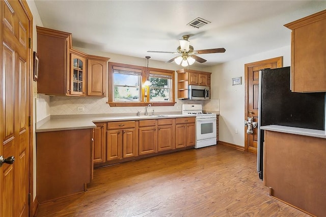 kitchen featuring ceiling fan, sink, white stove, refrigerator, and light hardwood / wood-style floors