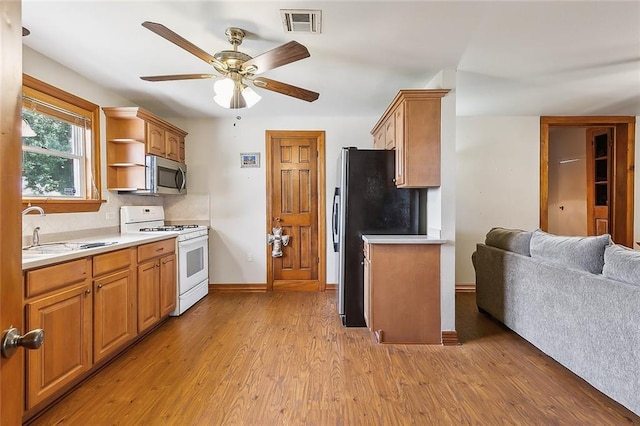 kitchen featuring light hardwood / wood-style floors, sink, decorative backsplash, appliances with stainless steel finishes, and ceiling fan