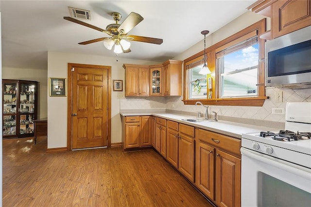 kitchen featuring ceiling fan, sink, white gas stove, light hardwood / wood-style floors, and decorative backsplash