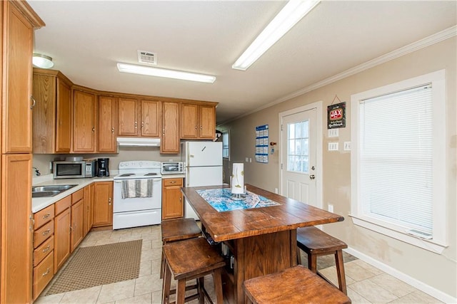 kitchen with crown molding, white appliances, light tile patterned flooring, and sink