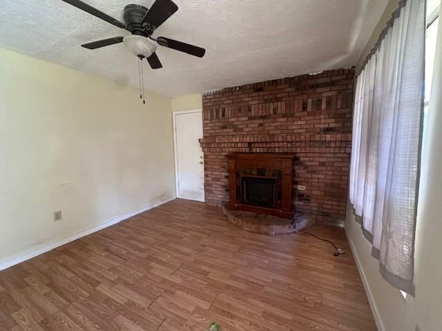 unfurnished living room with ceiling fan, a textured ceiling, a fireplace, and hardwood / wood-style floors