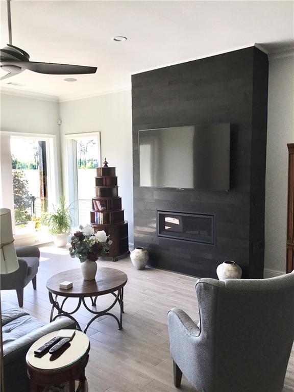106 Grand Champions Ln, Slidell, LA 70458 - living room featuring a glass covered fireplace, a ceiling fan, light wood-type flooring, and ornamental molding
